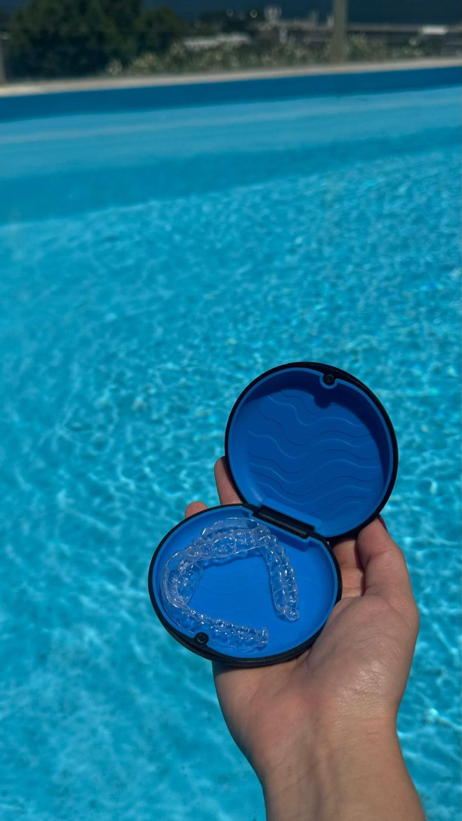 Estuche azul abierto con alineadores transparentes sobre el agua